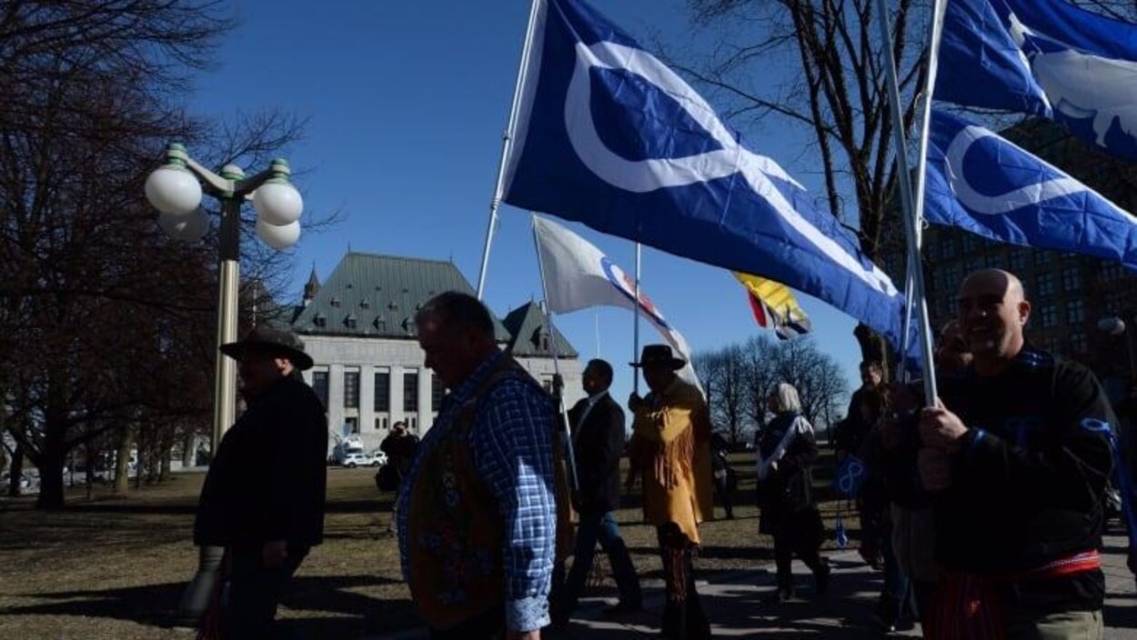 Des personnes tenant des drapeaux métis dans la main.