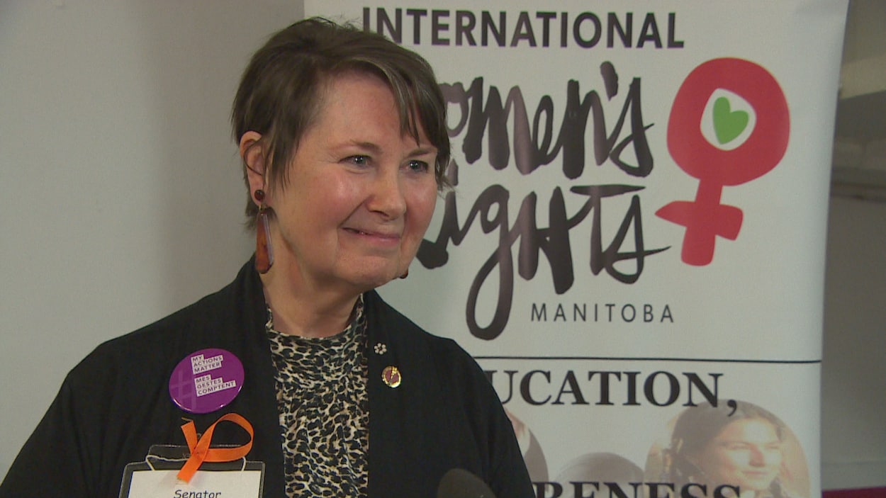 Photo de la sénatrice devant une bannière de l'Institut international pour les droits des femmes au Manitoba.