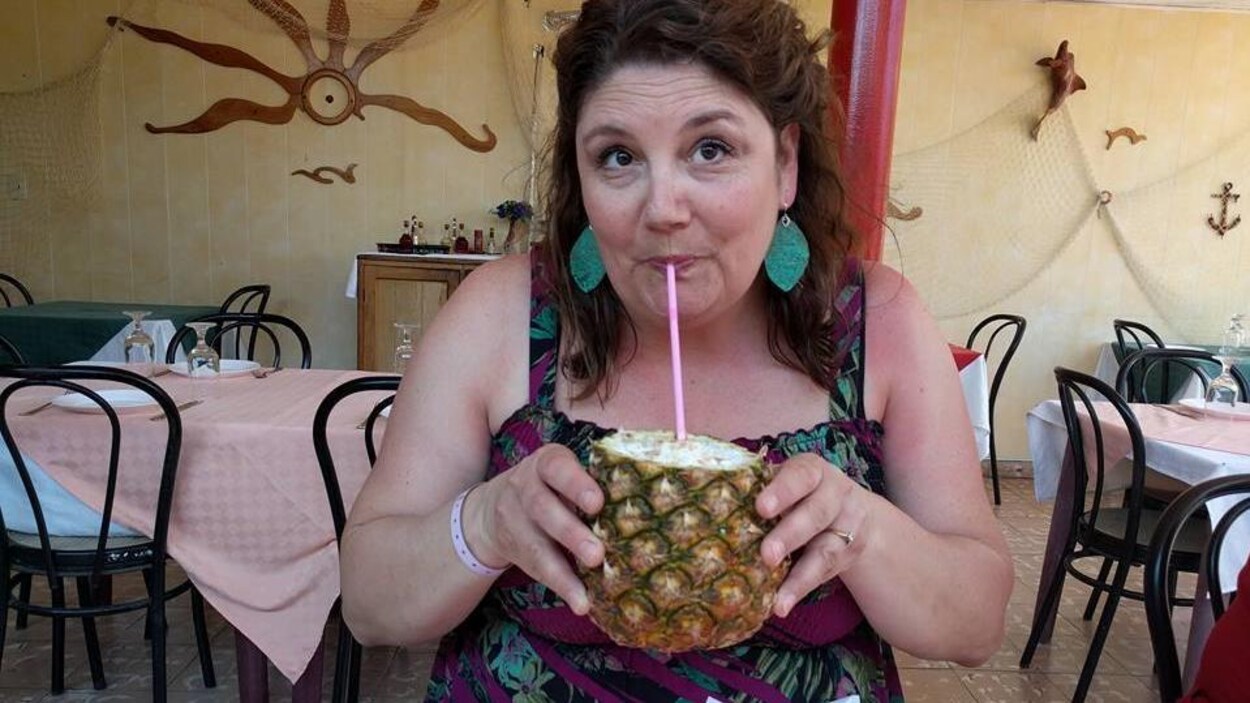 Une femme en train de boire une boisson tropicale dans un ananas Une femme en train de boire une boisson tropicale dans un ananas