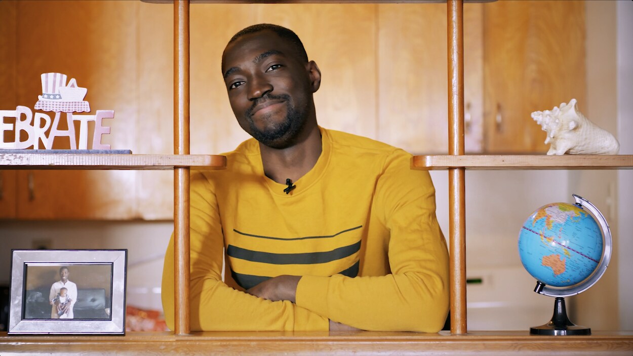 Un jeune homme de la Côte d'Ivoire avec les bras croisés et un sourire regarde directement vers la caméra