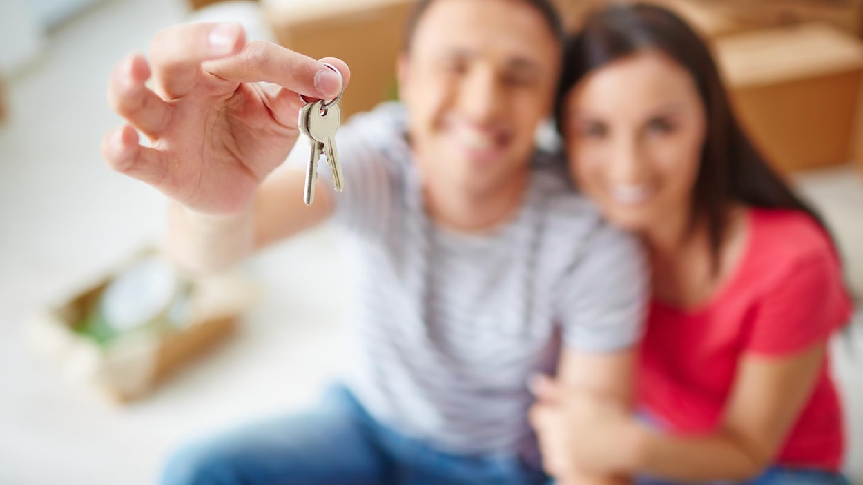 Un couple montre fièrement les clefs de sa nouvelle maison.