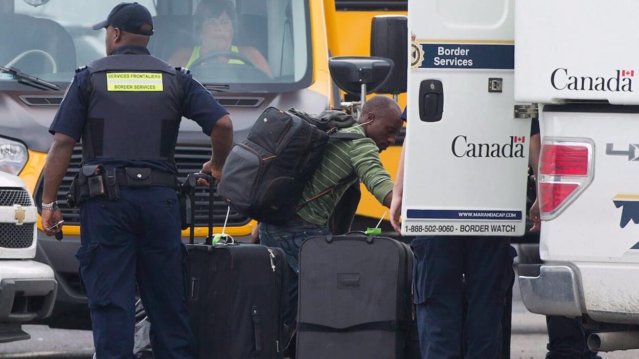 Un homme retire ses affaires d'un camion de l'ASFC dans un centre de traitement pour demandeurs d'asile.