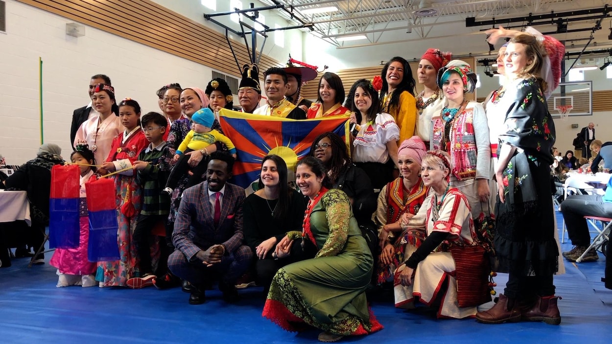 Une vingtaine de personnes de divers pays se tiennent debout pour une photo, la majorité porte des vêtements représentant leurs pays d'origine