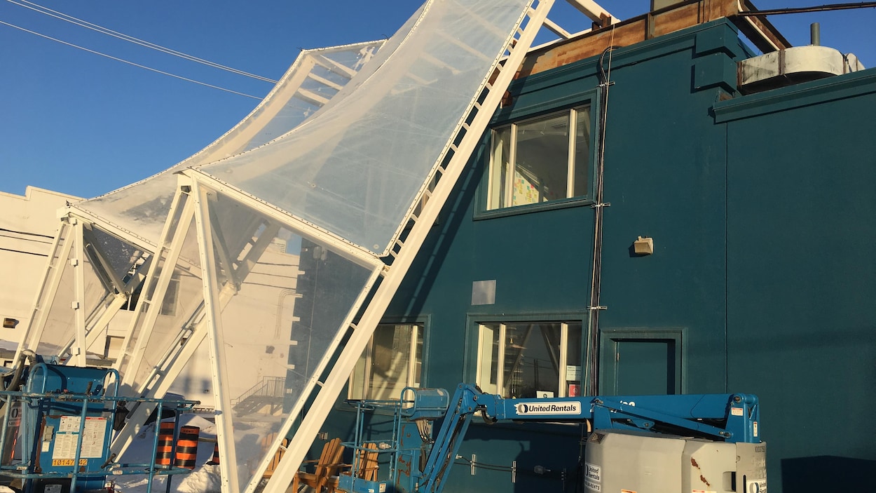 La structure en toile et en plastique rattachée aux bords d’un édifice permet d’abriter les passants du vent, de la neige et de la pluie.