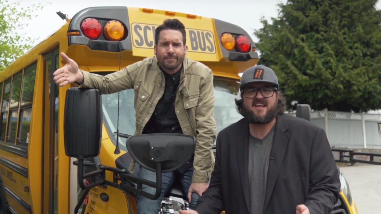 Capture d'écran d'un duo d'humoristes devant un autobus scolaire.