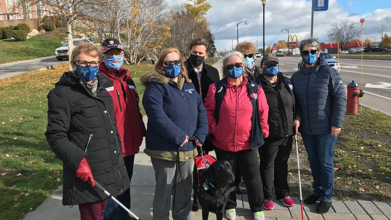Un regroupement de personne se trouvent avec le maire Yves Montigny, ainsi qu'un chien, juste à côté du feux de circulation sur le Boulevard Lasalle à Baie-Comeau.