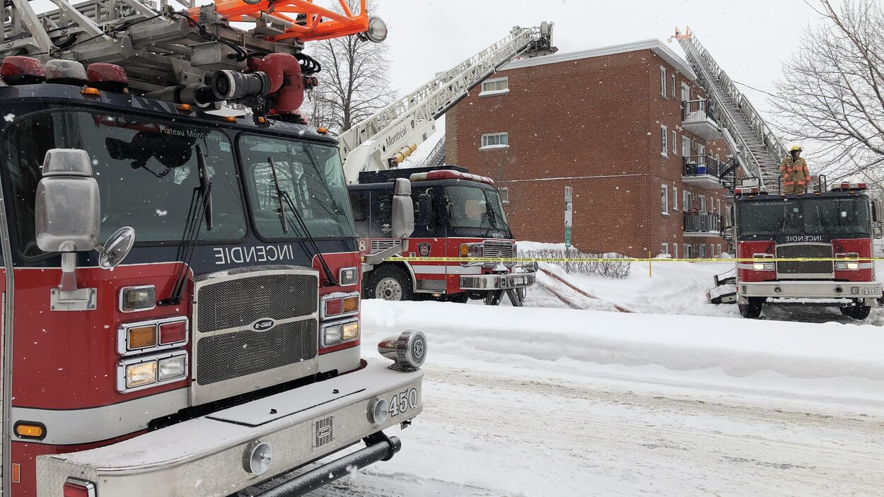 Trois camions de pompiers devant un immeuble.