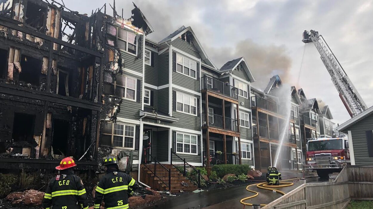 Des pompiers devant une aile calcinée de l'immeuble.