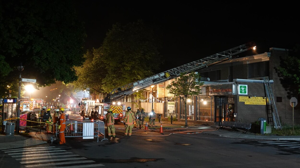 Des pompiers et leurs camions devant l'immeuble.