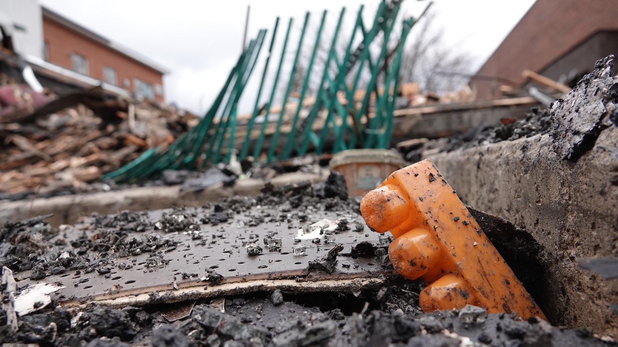 Un bloc jaune d'un jeu construction traîne parmi des débris incendiés.
