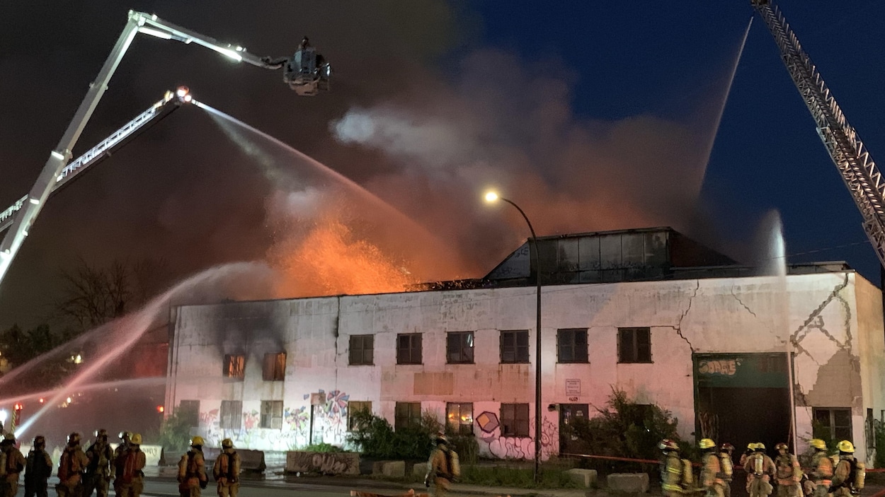 Des pompiers autour d'un bâtiment en feu.