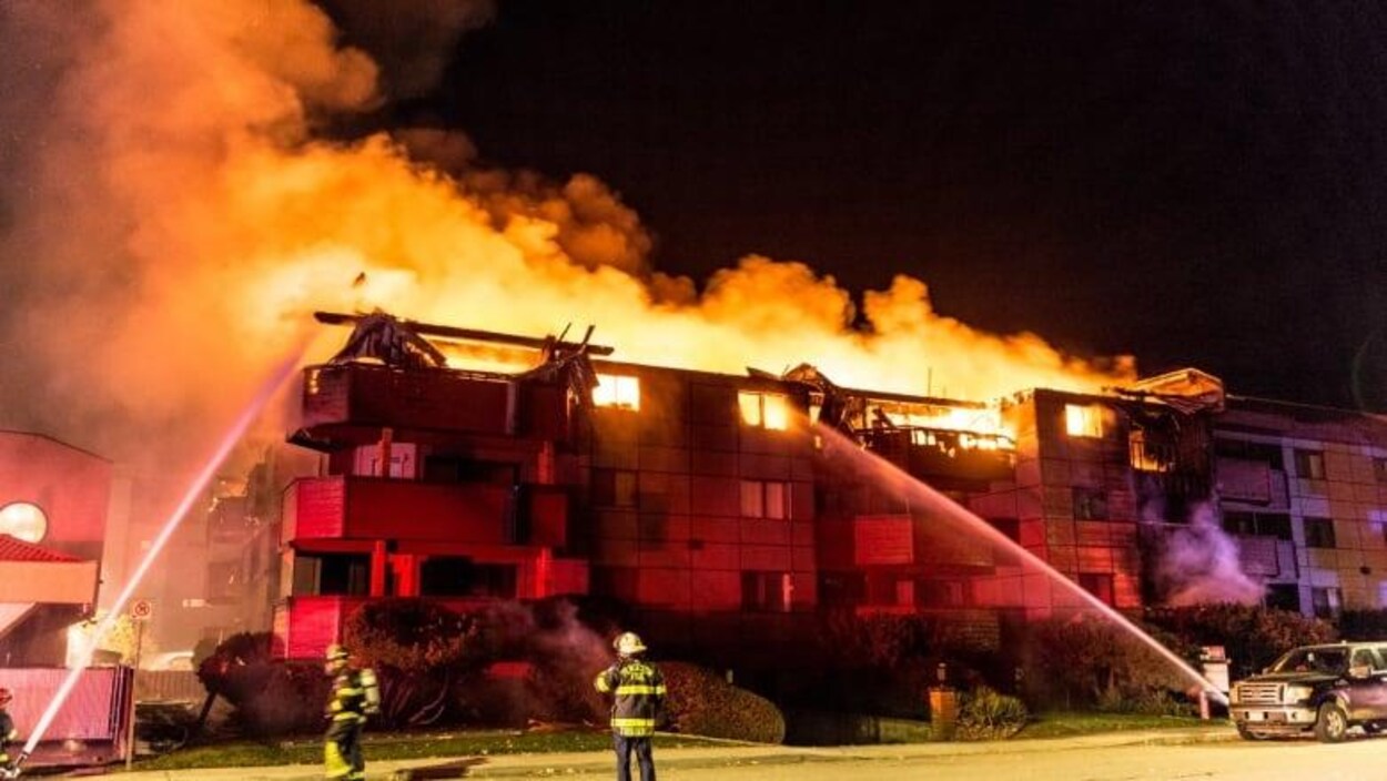 Des pompiers utilisent leurs lances à eau sur un immeuble en flammes.