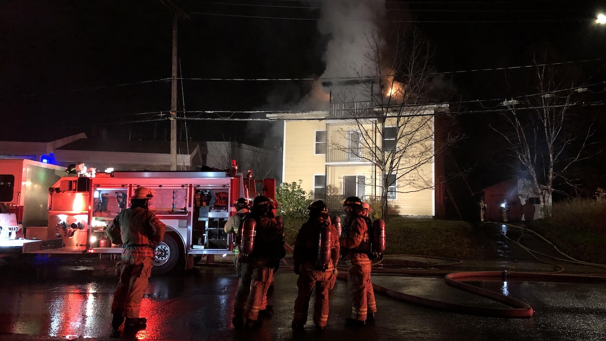 Des pompiers sont devant une résidence en flamme.