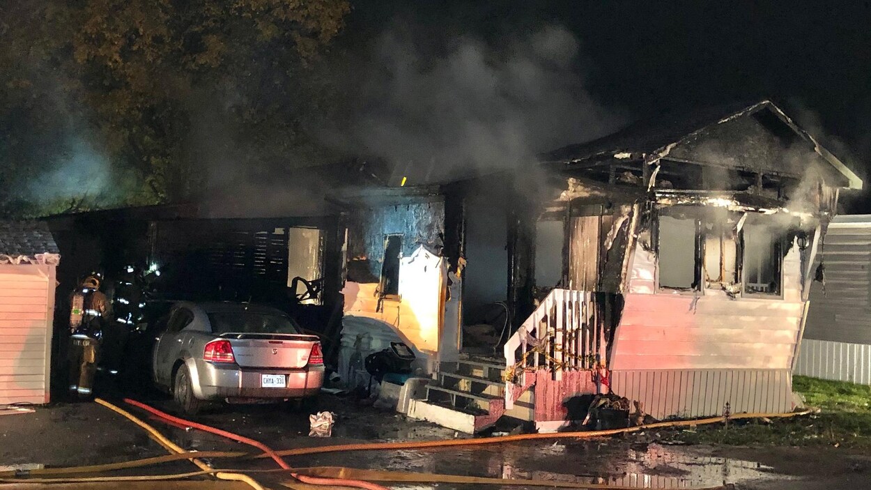 De la fumée s'échappe du toit et des fenêtres de la maison mobile.