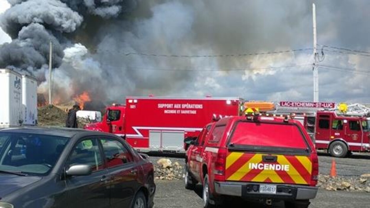 Plusieurs véhicules de pompiers devant un bâtiment en flamme