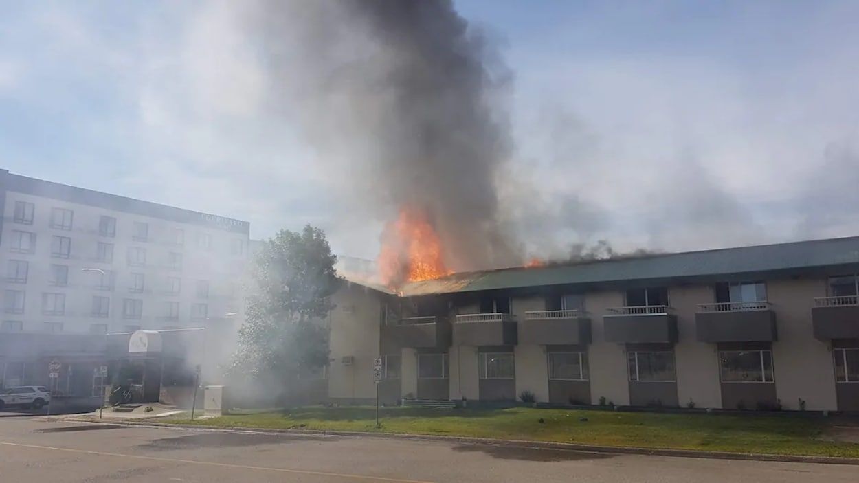 Des flammes et de la fumée jaillissent du motel de deux étages.