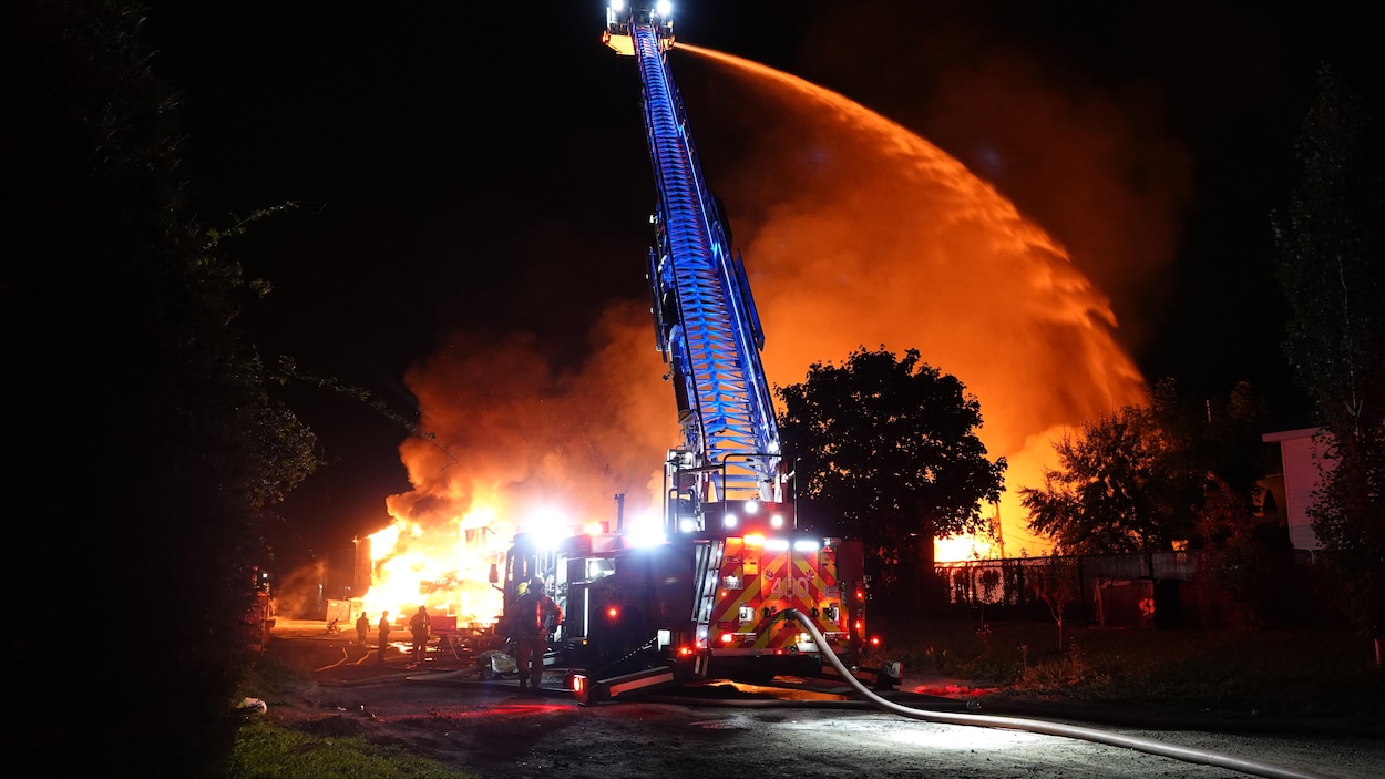 Les pompiers arrosent un gros incendie de la grande échelle d'un camion de pompier.