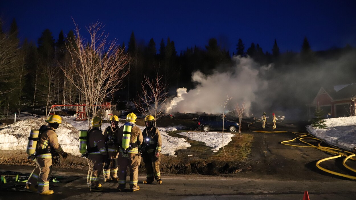 Des pompiers devant ce qui reste d'une résidence incendiée à Sainte-Brigitte-de-Laval.