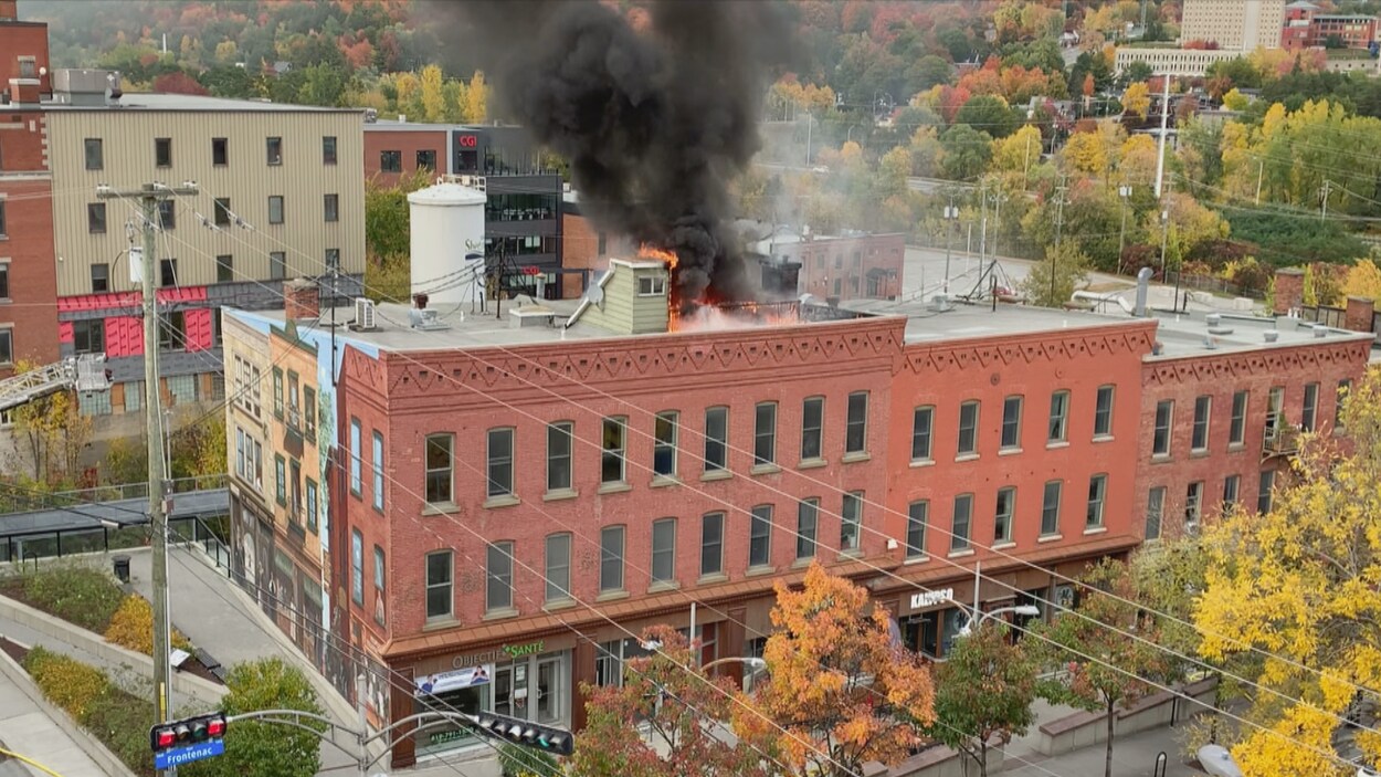 De la fumée noire et des flammes s'échappent du toit.