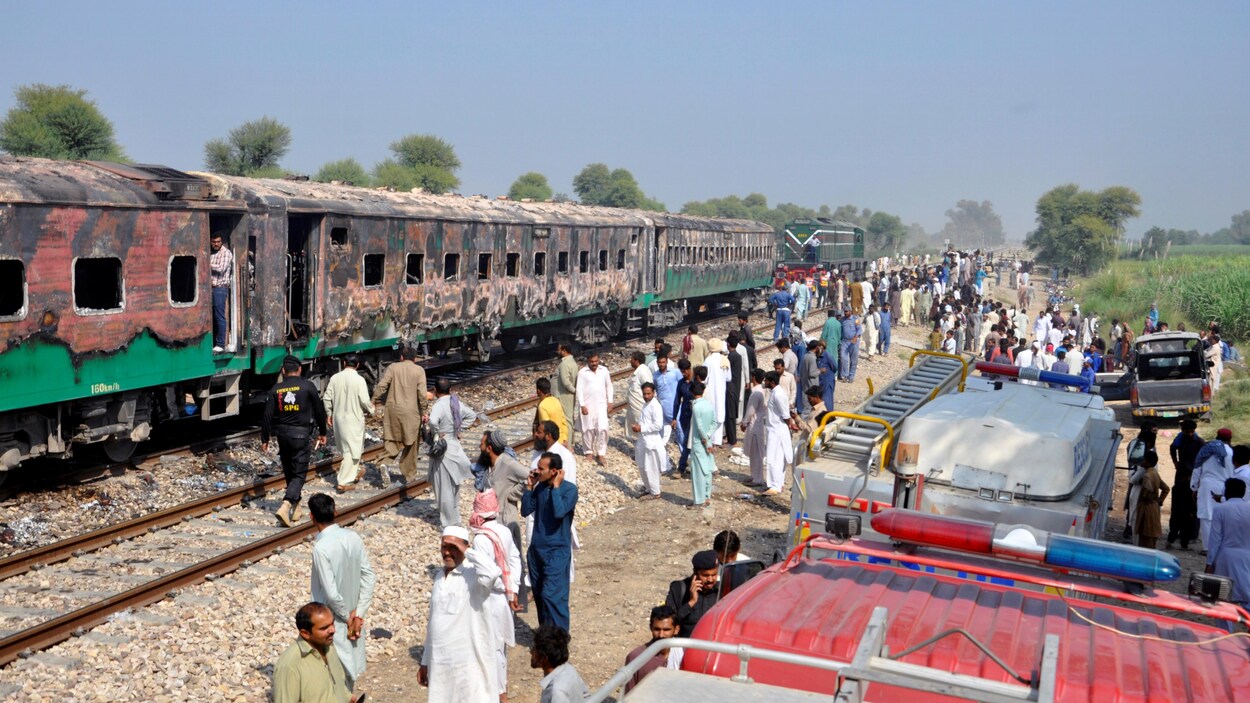 Des dizaines de personnes, voire des centaines, entourent la carcasse calcinée du train.