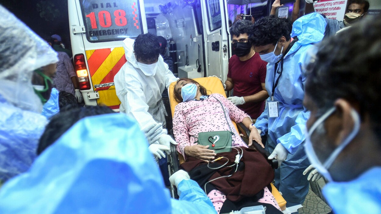 Une femme est couchée sur une civière devant la porte arrière d'une ambulance.