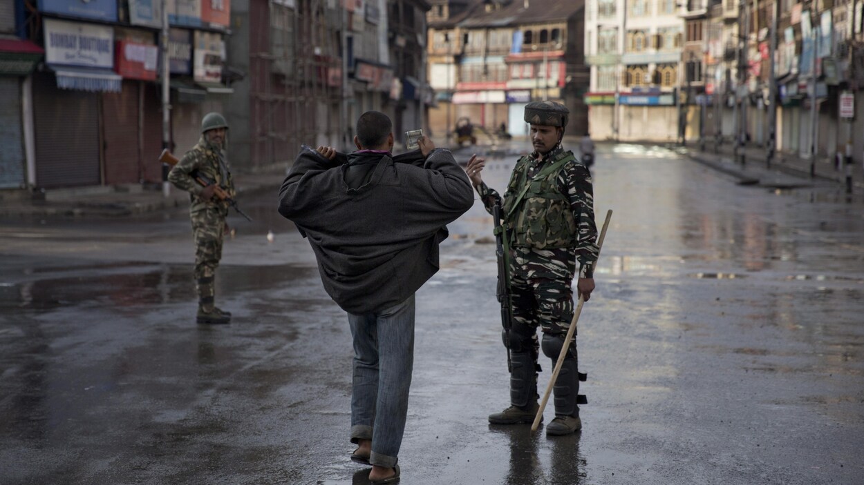 Un paramilitaire indien inspecte un Cachemiri pendant le couvre-feu à Srinagar.