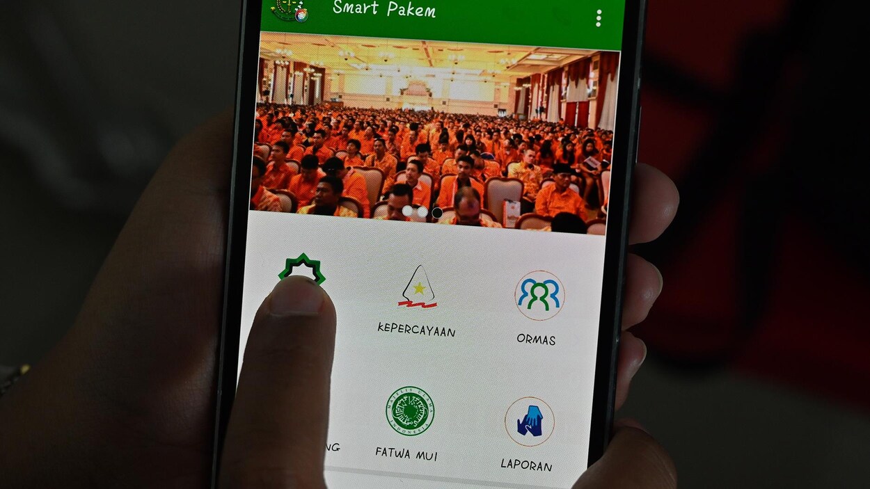 Une femme montre du doigt le symbole d'une application sur un téléphone intelligent.