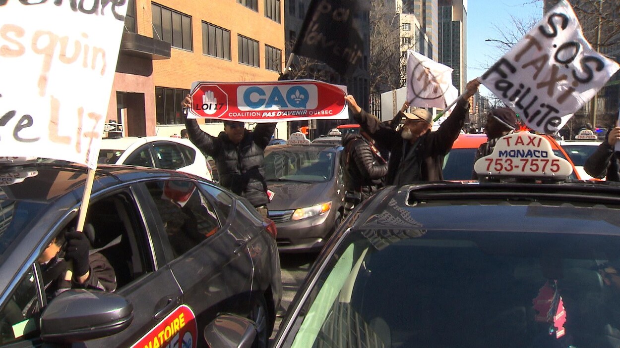Des chauffeurs de taxis ont manifesté vendredi devant les bureaux du ministère des Transports, sur le boulevard René-Lévesque Ouest, à Montréal.