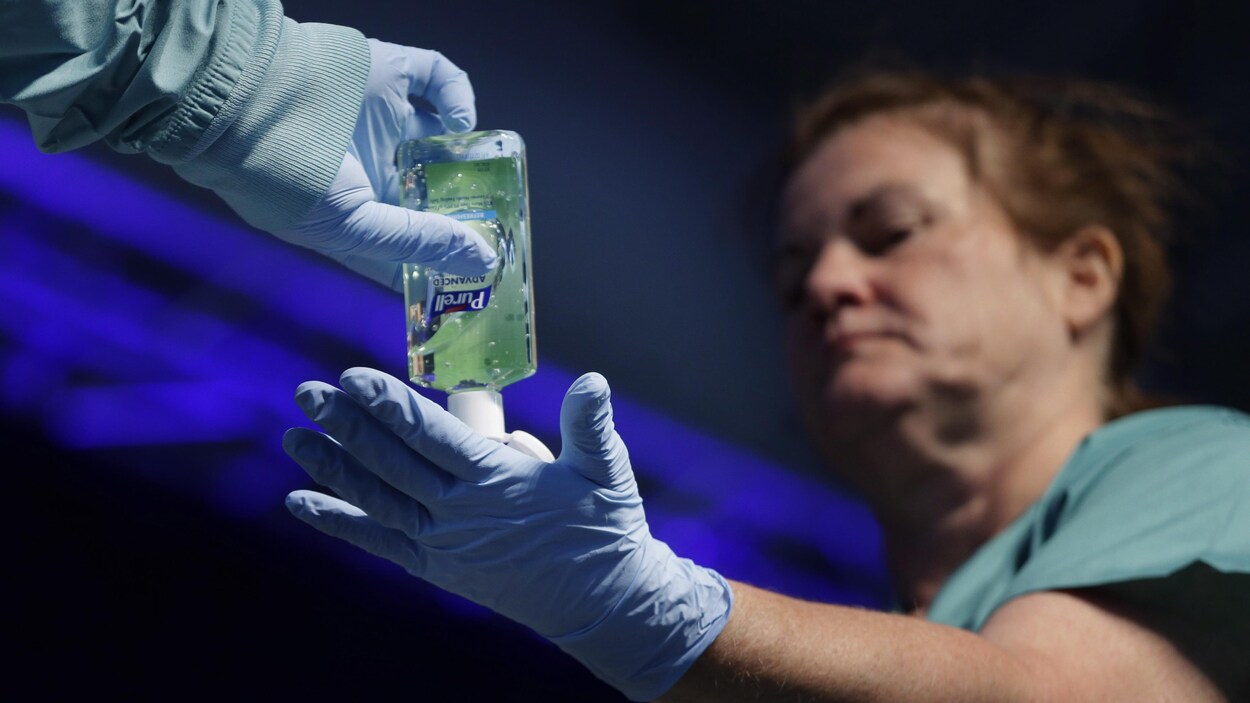 Une infirmière désinfecte ses gants avec du gel antiseptique.