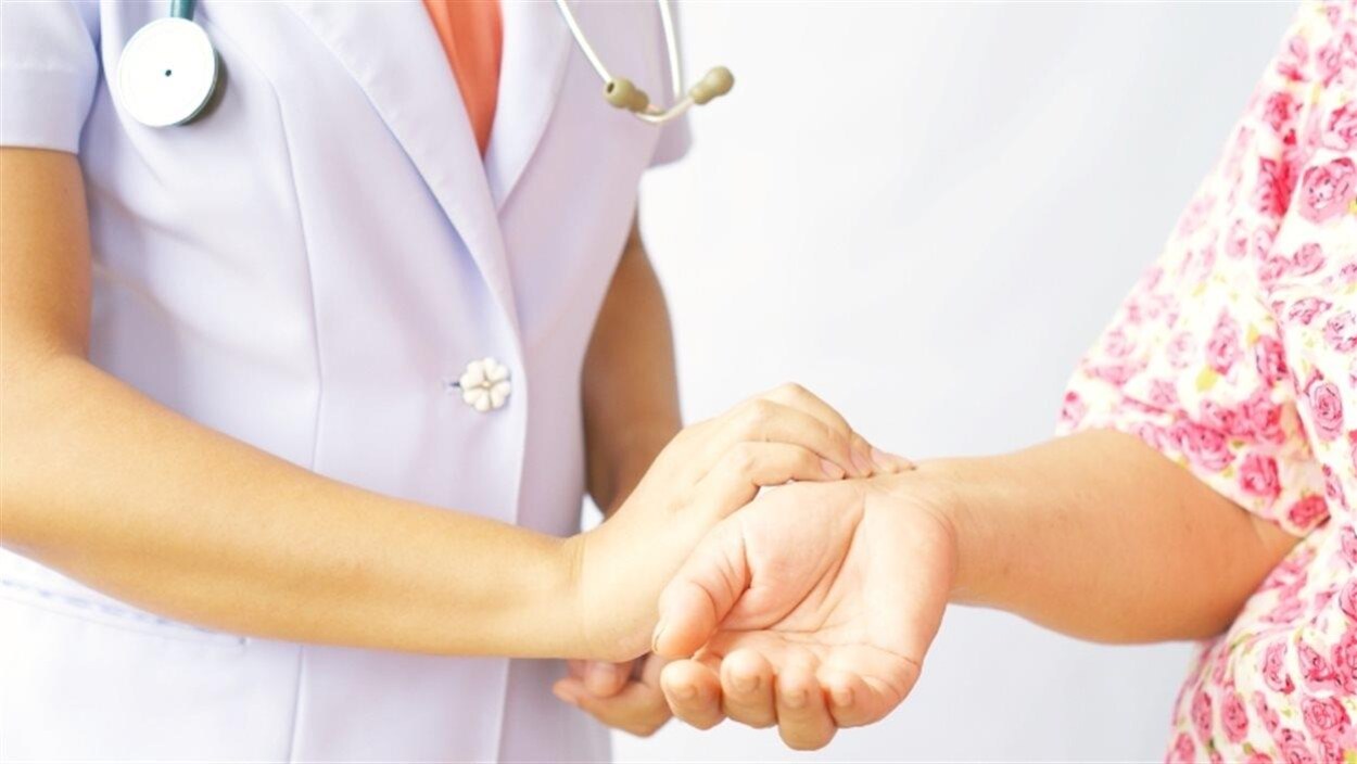 Une infirmière prend le pouls d'une femme.