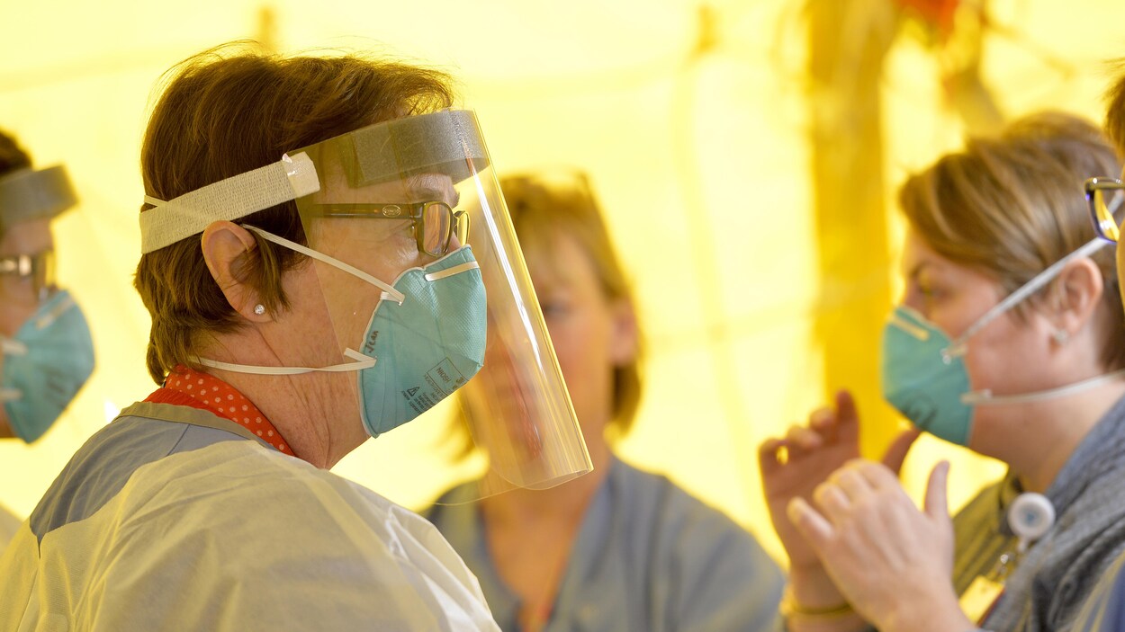 Des infirmières mettent leur équipement de protection avant de tester les patients pour le coronavirus