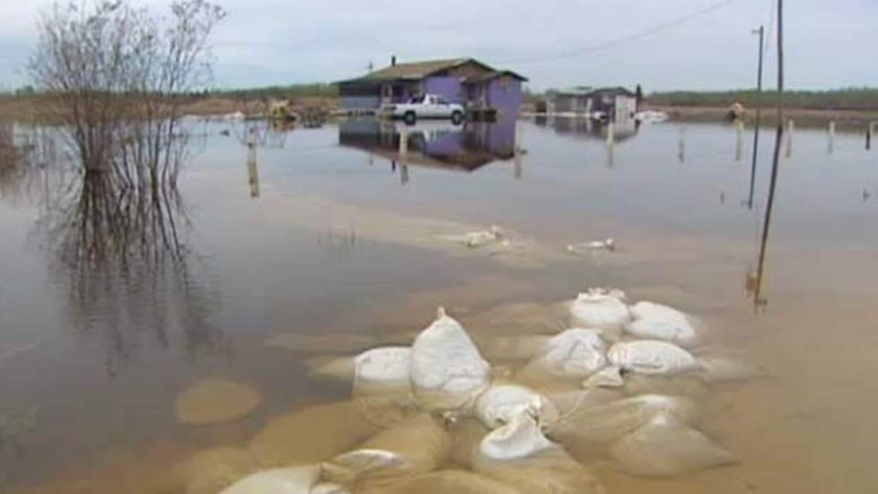 Des sacs de sable devant une maison dans la Première Nation de Little Saskatchewan au Manitoba, touchée par une inondation en 2011. Des sacs de sable devant une maison dans la Première Nation de Little Saskatchewan au Manitoba, touchée par une inondation en 2011.