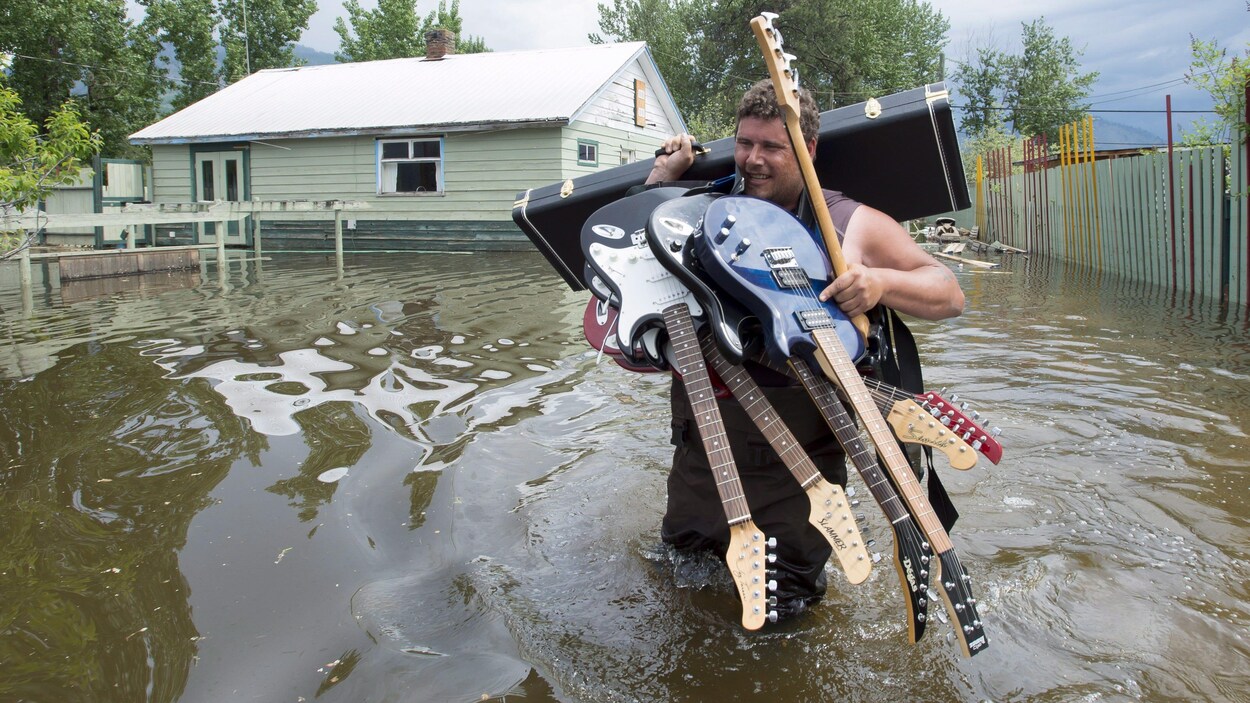 Un homme transporte des guitares dans une zone inondée. Un homme transporte des guitares dans une zone inondée.