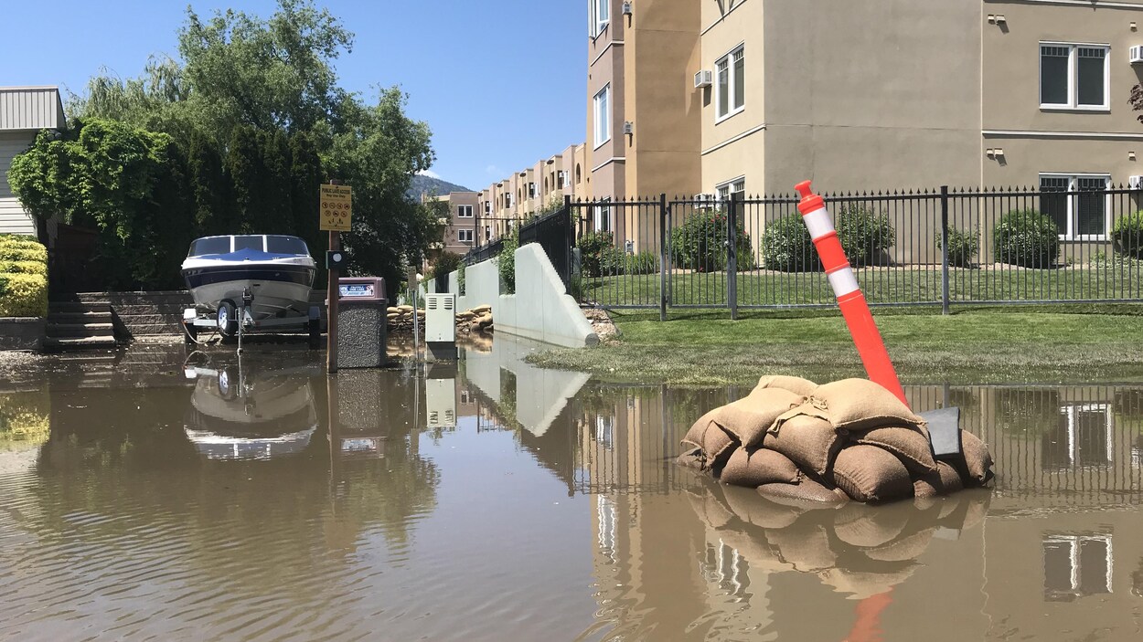 Un immeuble derrière une cour inondée, des sacs de sable et un bateau. Un immeuble derrière une cour inondée, des sacs de sable et un bateau.