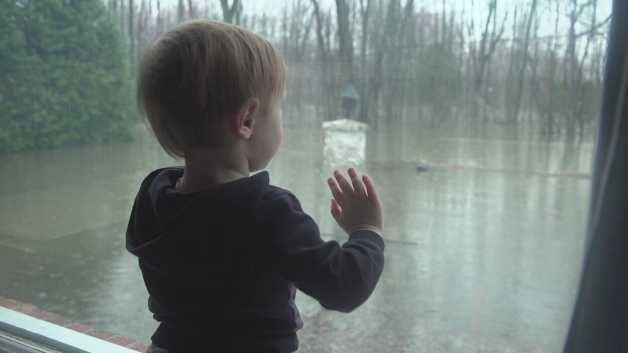 Un enfant appuyé à une fenêtre.