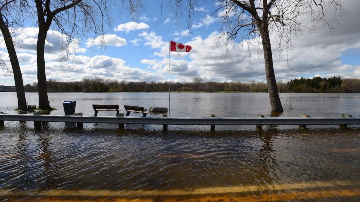 Route et berges d'une rivière engloutie en raison d'inondations.