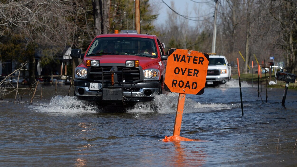 Des camionnettes et une enseigne sur une route inondée Des camionnettes et une enseigne sur une route inondée