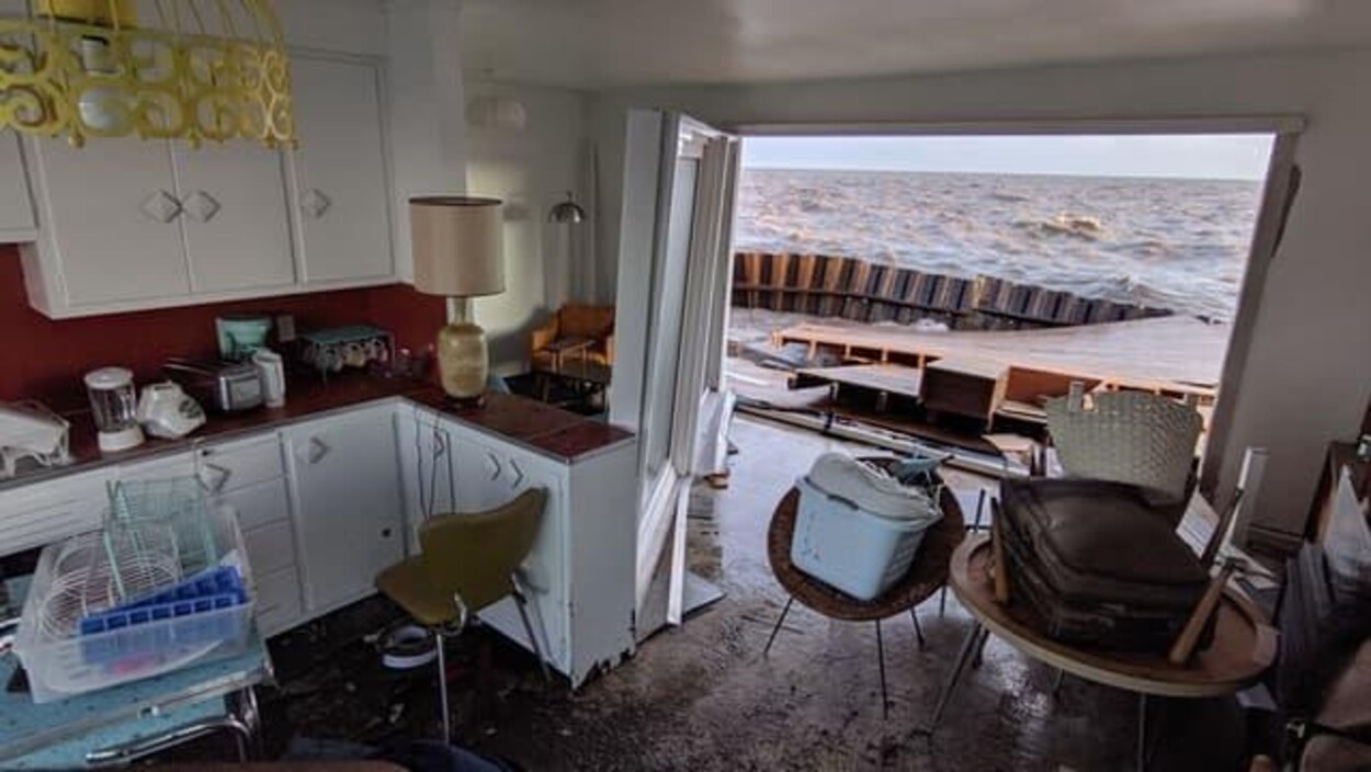 Intérieur d'une maison en désordre. La porte-fenêtre est ouverte.