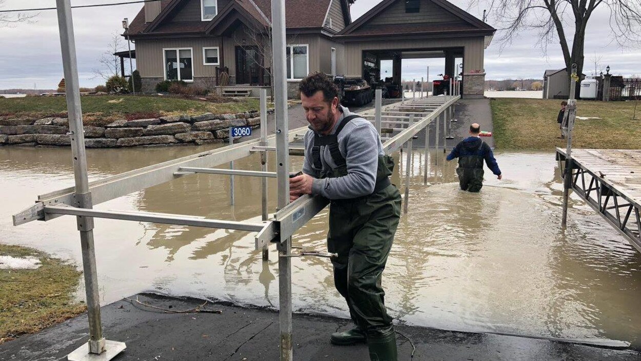Deux hommes construisent un pont alors qu'ils ont de l'eau aux genoux.