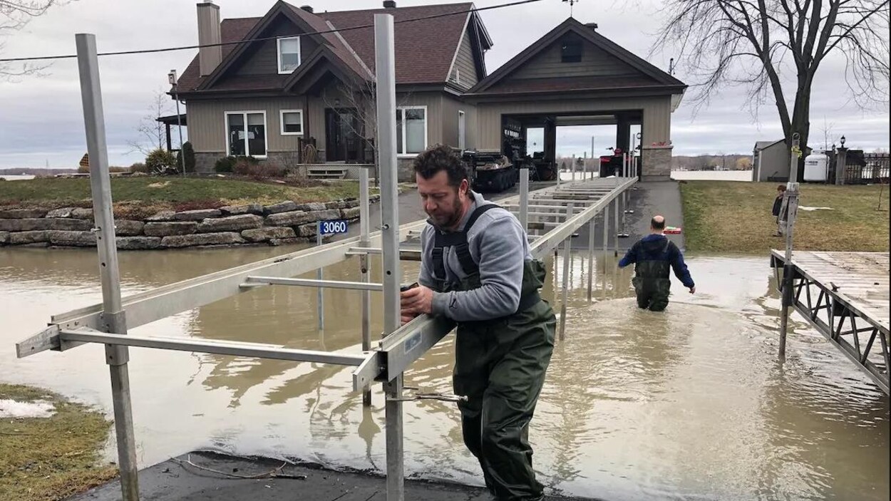 Un homme stabilise une structure en métal reliant la route à une résidence.