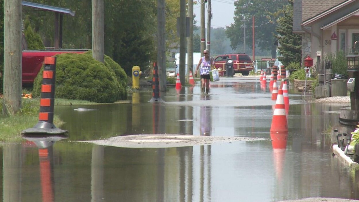 Une femme marche en botte de pluie dans une rue inondée