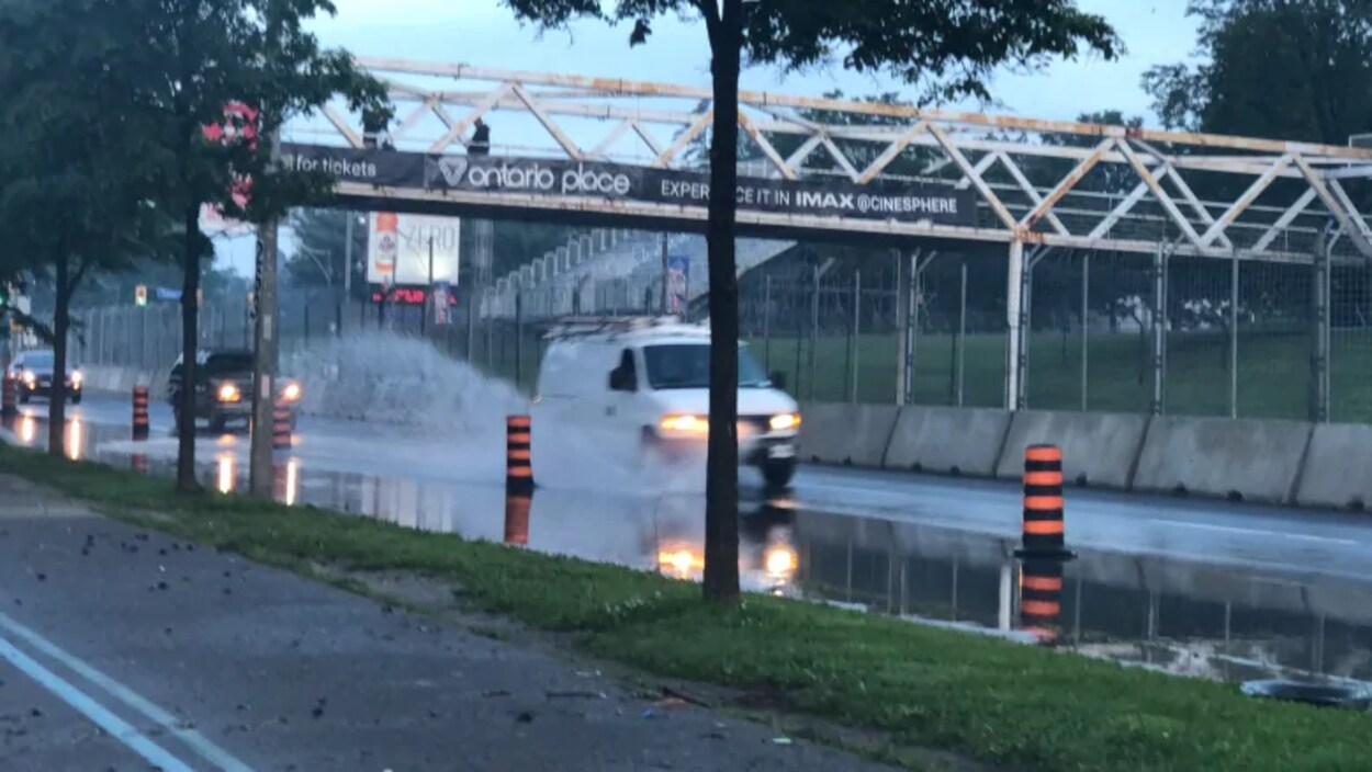 Photo d'une camionnette blanche qui projette de l'eau dans les airs en roulant dans une flaque d'eau.