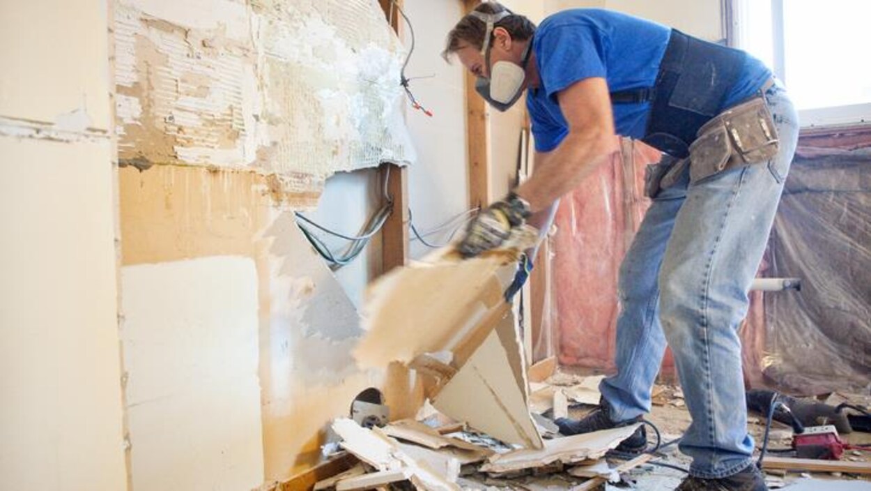 Un homme arrache un mur en contreplaqué.