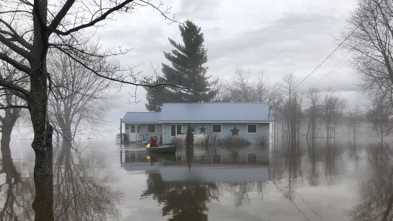 Une personne quitte sa maison en canot.