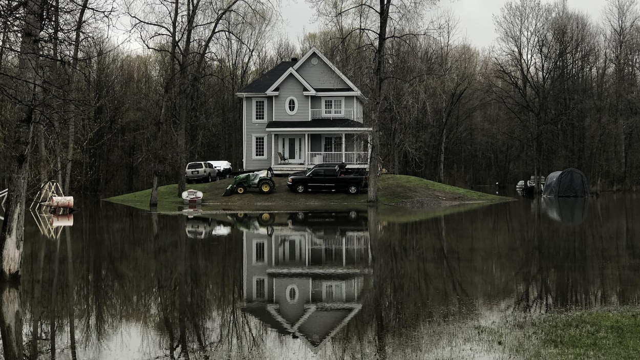 Une maison de deux étages sur une butte de terre entourée par l'eau