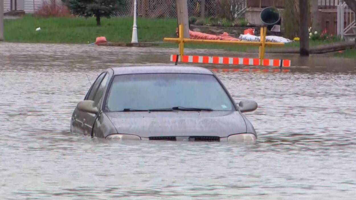 Une automobile abandonnée dans un mètre d'eau au milieu de la route.