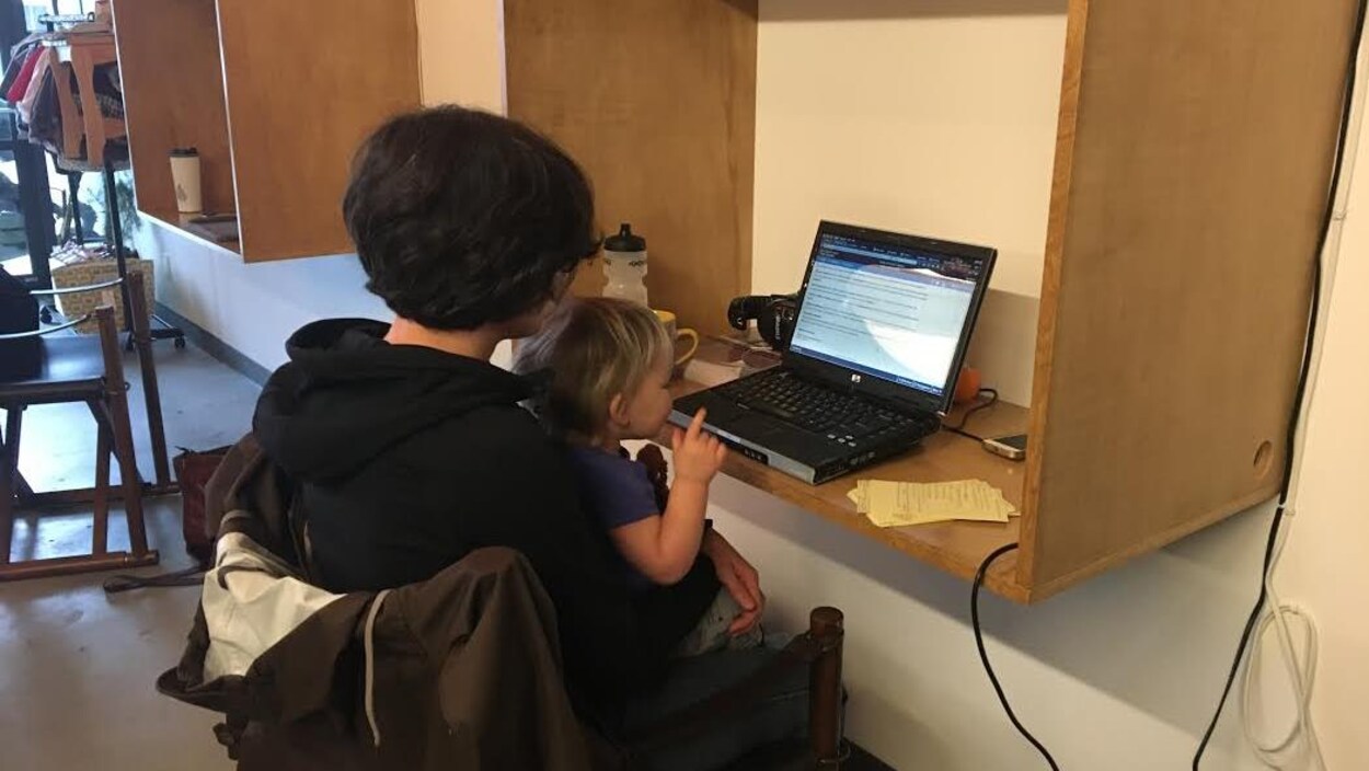Une femme et sa fille sont de dos devant un ordinateur.