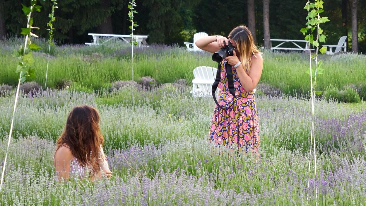 Une jeune femme se fait photographier en contre-plongée de dos dans un champ de lavande. Des ballons enjolivent la scène.