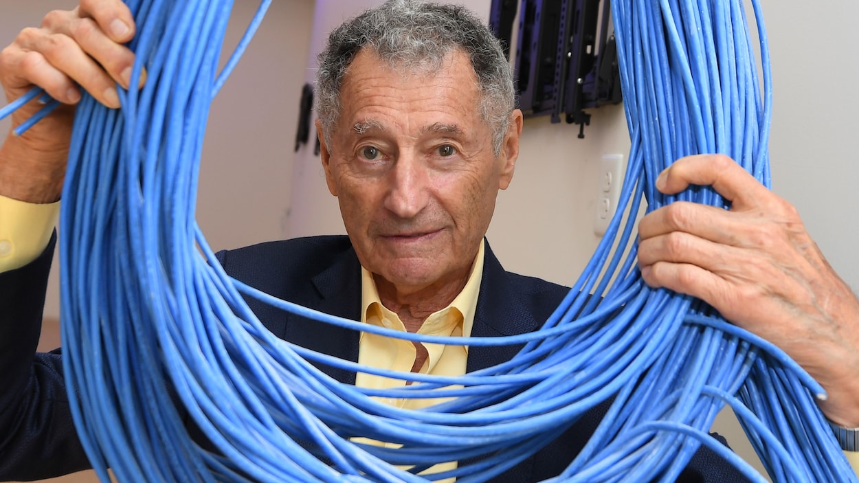 Un homme tient un rouleau de câbles réseau.