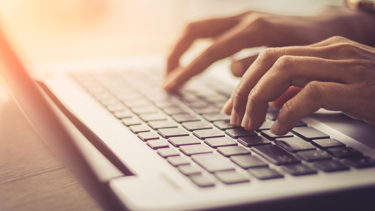 Une personne tape sur le clavier d'un ordinateur.